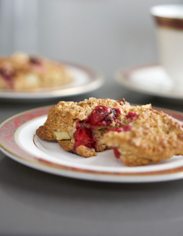 scone broken apart showing juicy cranberries on a red rimmed china plate