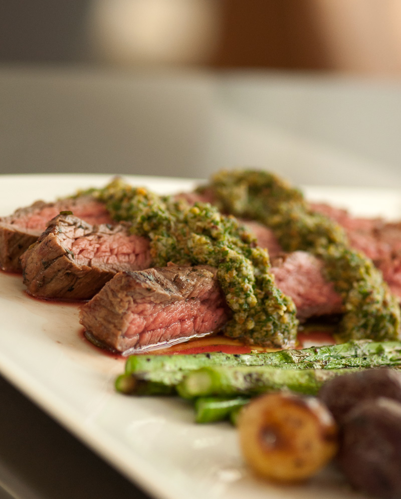 Juicy steak with pesto, plated with asparagus and baby potatoes