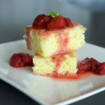2 cake squares topped with strawberry basil compote, with juices soaking into the cake