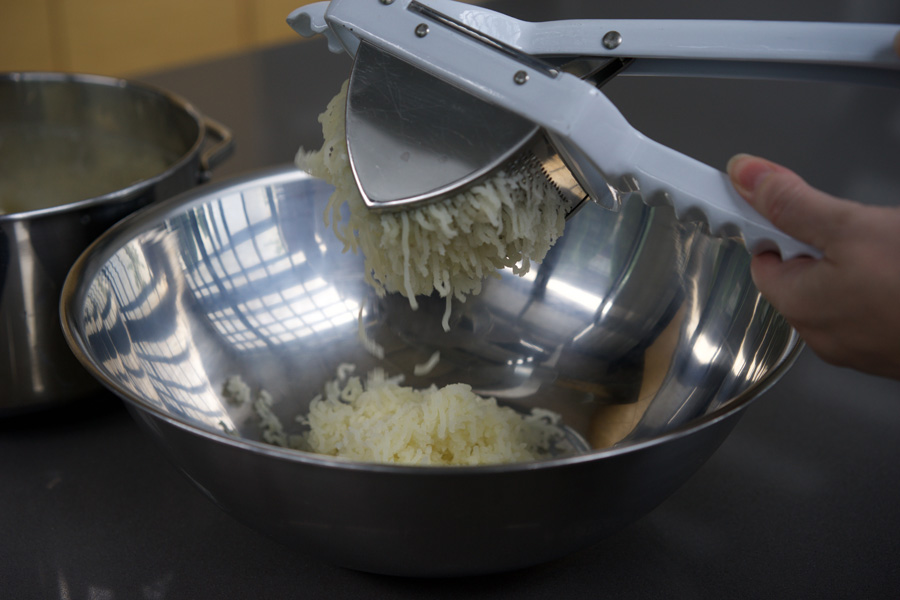 Potatoes are fed through a heavy-duty ricer