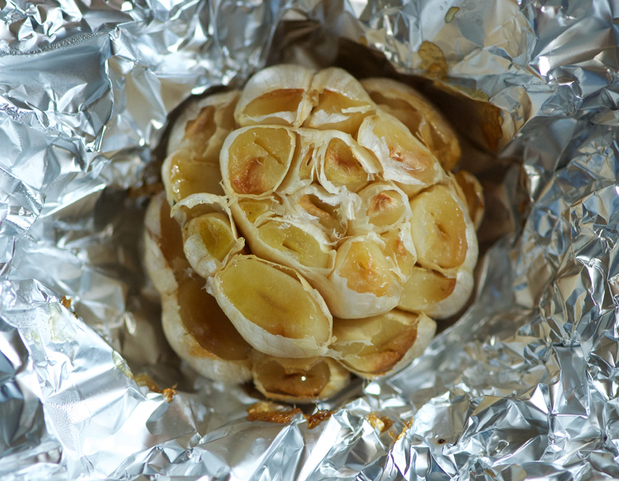 Fresh from the oven, a head of roasted garlic in crinkly foil