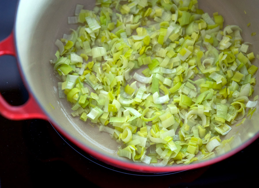 Leeks and garlic gently cooking in a red pot