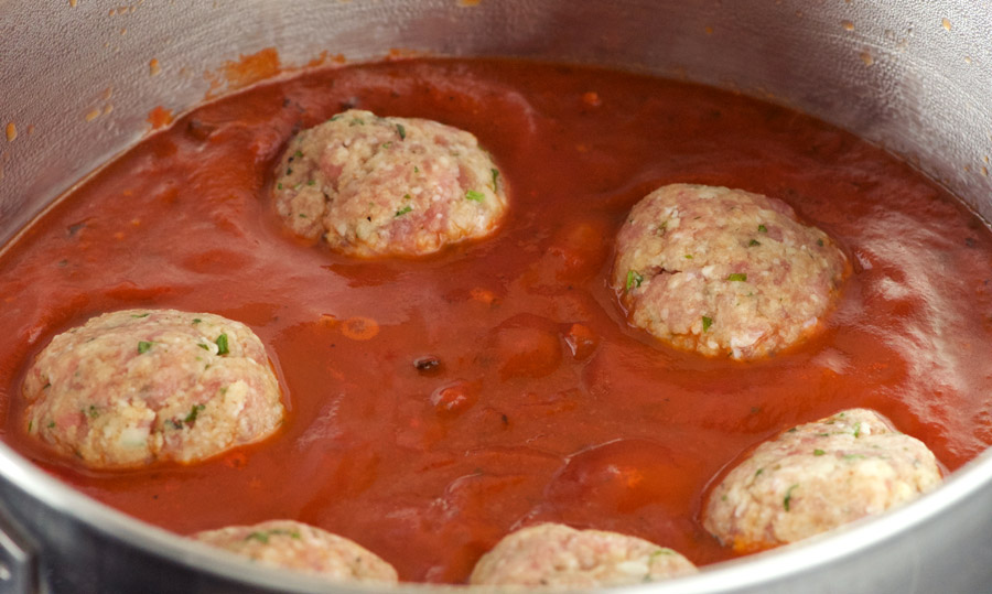 Cooking meatballs in bubbling tomato sauce