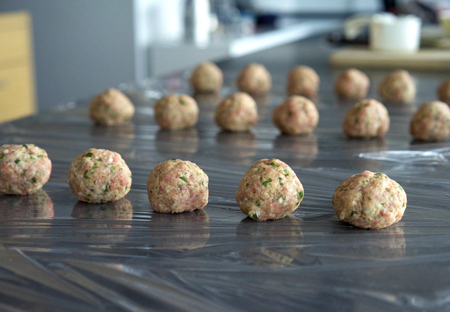 Assembly line of turkey meatballs ready to be wrapped and frozen as meal prep