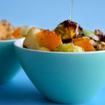 Drizzling maple syrup on roasted brussels sprouts with squash and apples