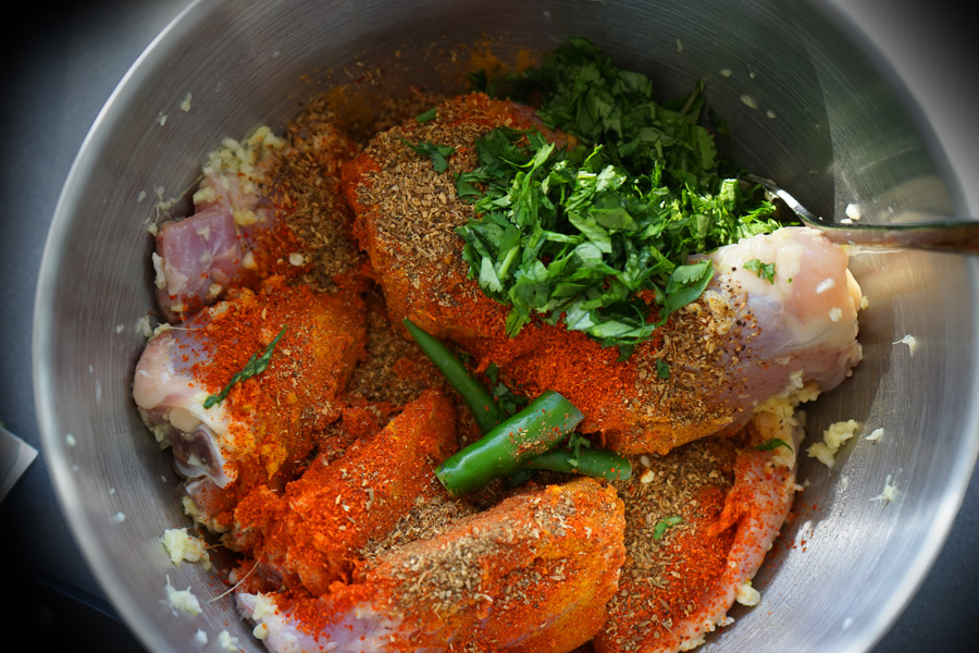 Chicken and bright red and green spices layered in a bowl